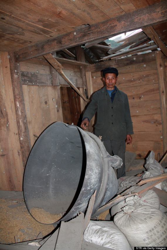 This picture taken on December 2, 2013 shows a man pointing to debris from the rocket carrying China's first moon rover in a house in Suining, central China's Hunan province. The debris plummeted to earth in a village more than a thousand kilometres from the launch site, crashing into two homes, a report said on December 3, 2013. CHINA OUT AFP PHOTO (Photo credit should read STR/AFP/Getty Images)