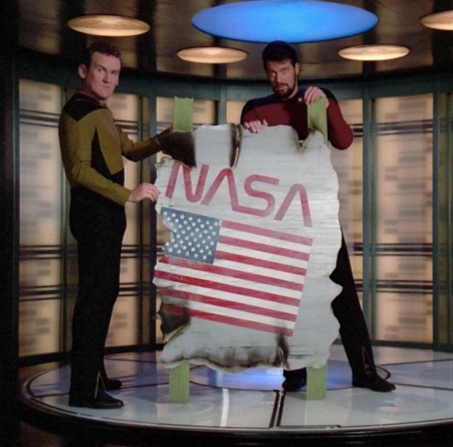 O'Brien e Riker transportam destroço de nave com a marca antiga da NASA. 