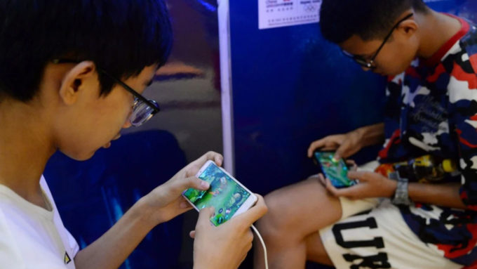 Garotos jogam Honor of Kings, jogo mobile distribuído pela Tencent, durante evento em Shopping Center na China (Crédito: Reuters)
