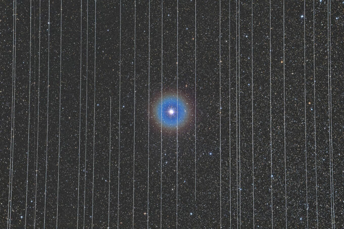 Foto "A Prisão da Tecnologia", vencedora do prêmio de Fotografia Astronômica de 2020; a estrela binária Albireo, na constelação de Cisne, atrás das "grades" de diversos rastros dos satélites da Starlink (Crédito: Rafael Schmall)