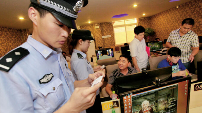 Policiais checam documentos em lan house na cidade de Zaozhuang; oficiais costumam deter quem usa a internet para criticar a polícia e/ou o governo chinês (Crédito: Ji Zhe/Imaginechina/AP Images)