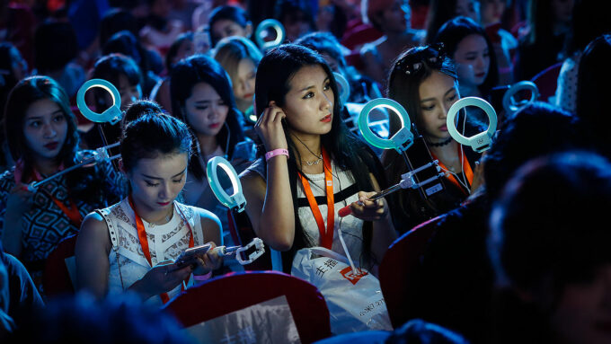 Jovens chinesas realizam streaming de vídeo durante evento da Xiaomi em Pequim, em foto de 2016 (Crédito: Liu Xingzhe/Eyes on China)