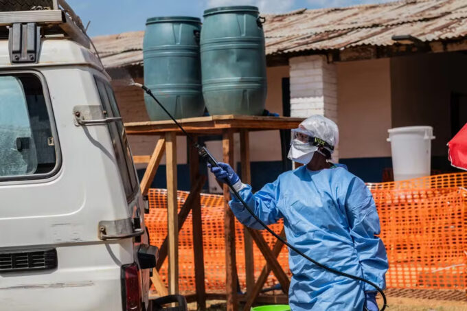 Profissional de saúde desinfeta ambulância usada para transportar paciente com suspeita de Ebola para o centro de tratamento de Mongbwalu, na RDC (Crédito: Moses Sewasawa/AP)