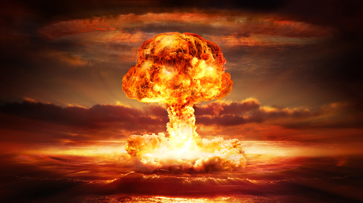 Uma composição digital que simula uma explosão nuclear em um ambiente marítimo ou costeiro durante o crepúsculo. A cena é dominada por uma coluna central de fogo e fumaça que se eleva verticalmente, formando a clássica estrutura de um cogumelo nuclear. A base da explosão, no nível do horizonte, apresenta uma nuvem densa e branca, quase translúcida, onde a luz é mais intensa e branca, sugerindo o ponto de impacto. A partir dessa base, uma longa cauda de fumaça ascendente conecta-se à cabeça da nuvem.A "cabeça" ou parte superior da explosão é a característica mais volumosa e detalhada. Ela tem uma forma arredondada e irregular, lembrando uma massa de nuvens ou uma bolha gigante. A textura é complexa, com múltiplas camadas de fumaça e incêndio. As cores são predominantemente tons quentes: laranjas vibrantes, amarelos intensos e vermelhos profundos. Há variações de brilho, com áreas centrais muito claras (quase brancas) que indicam o centro da combustão, transicionando para tons de laranja e vermelho nas bordas e na parte externa da nuvem. Ao redor da cabeça da nuvem, as bordas são mais difusas e misturam-se com o céu ao fundo.O céu ao fundo exibe uma paleta de cores que complementa a explosão, mas com tons mais frios e suaves. Predominam tons de marrom avermelhado, laranja escuro e cinza chumbo. Há nuvens espalhadas no céu, com texturas mais suaves e formas alongadas, sugerindo movimento ou distorção causada pela onda de choque ou pelo calor. A iluminação geral da cena é quente e dramática, vinda da própria explosão, que atua como a fonte de luz principal, iluminando o céu e as nuvens ao redor. A luz cria um brilho suave e difuso no horizonte, especialmente na parte inferior da imagem.Na parte inferior da imagem, abaixo da coluna de fumaça, observa-se uma superfície que parece ser a água do mar ou uma área plana de terra molhada. Ela reflete a luz dourada e alaranjada da explosão, criando um brilho intenso e espelhado. A superfície tem uma textura ondulada, sugerindo ondas ou vapor subindo. A composição é simétrica em relação ao eixo vertical da explosão, com a coluna central alinhada ao centro da imagem. O fundo é mais escuro nas laterais e no topo, criando um enquadramento natural que direciona o olhar para o centro da ação. A profundidade é sugerida pela sobreposição da nuvem de fumaça sobre as nuvens do céu e pela reflexão na superfície inferior. O estilo visual é de uma renderização 3D ou de um efeito digital avançado, com texturas realistas de fumaça e fogo, mas com uma atmosfera estilizada e dramática, típica de filmes ou arte conceitual.